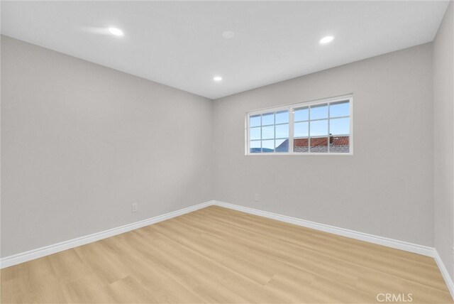 empty room featuring baseboards, light wood-type flooring, and recessed lighting