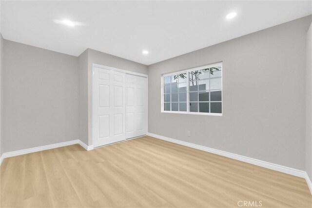 unfurnished bedroom featuring baseboards, a closet, light wood-type flooring, and recessed lighting