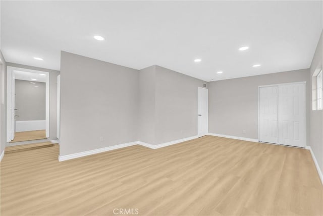 empty room featuring baseboards, light wood-style floors, and recessed lighting