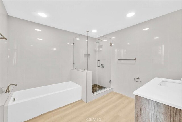 full bath with a shower stall, wood finished floors, a bath, recessed lighting, and a sink