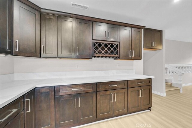 indoor dry bar featuring light wood-type flooring, stairs, and baseboards