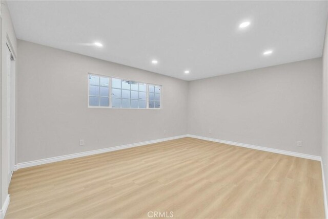 empty room featuring light wood-type flooring, baseboards, and recessed lighting