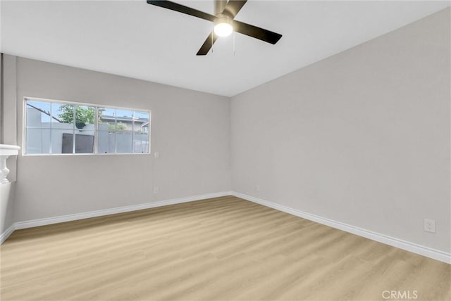 spare room featuring light wood-style floors, baseboards, and a ceiling fan
