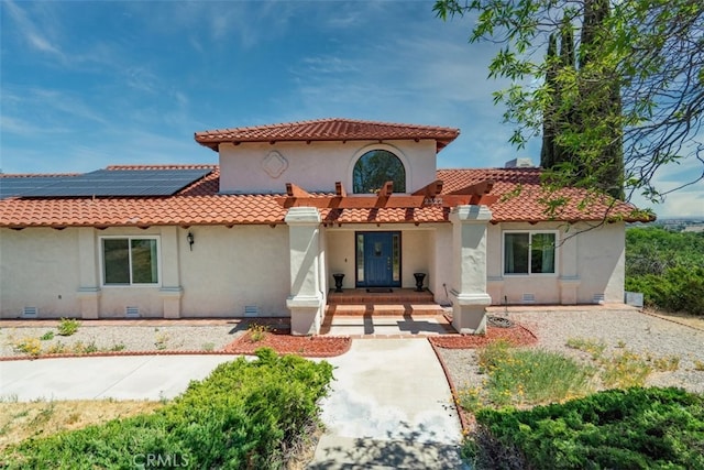 back of house with stucco siding, solar panels, and a tile roof