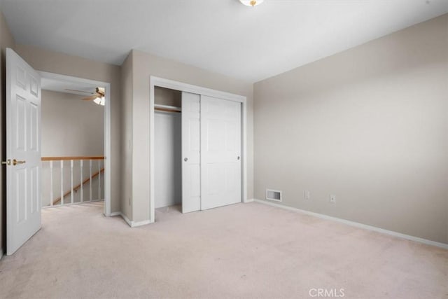 unfurnished bedroom featuring light colored carpet, a closet, and baseboards