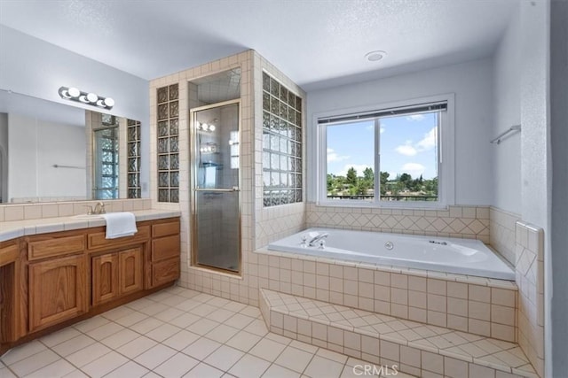 bathroom with tile patterned floors, a shower stall, vanity, a garden tub, and a textured ceiling