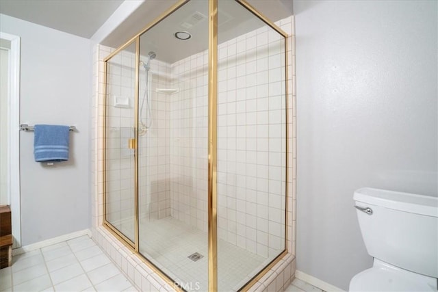 bathroom with a stall shower, toilet, and tile patterned floors