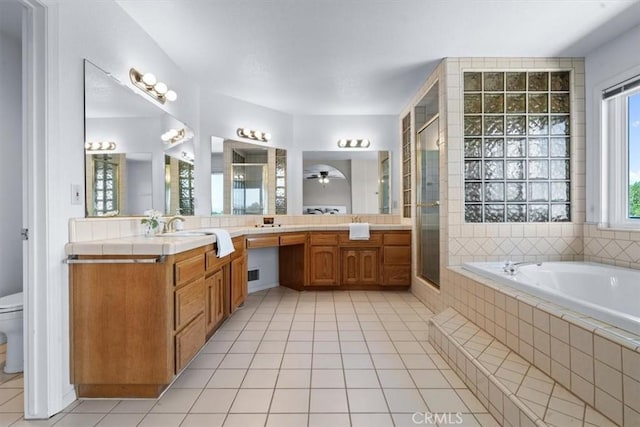 bathroom featuring tile patterned floors, a shower stall, a garden tub, and toilet
