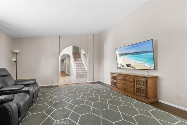living room with arched walkways, baseboards, stairs, and wood finished floors