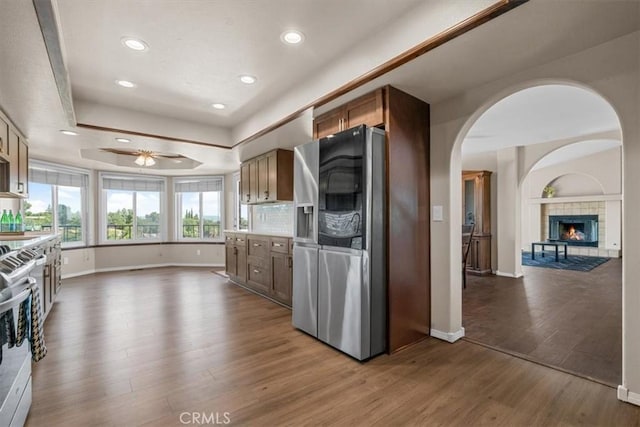 kitchen featuring stainless steel appliances, open floor plan, baseboards, wood finished floors, and a tile fireplace