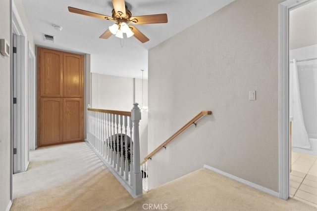 stairs with carpet flooring, ceiling fan, a textured wall, and baseboards