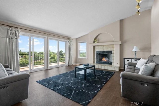living room with vaulted ceiling, a tile fireplace, and wood finished floors