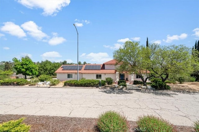 view of front of home with a tiled roof, solar panels, and stucco siding