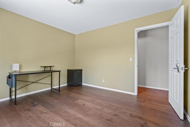 unfurnished bedroom featuring wood finished floors and baseboards