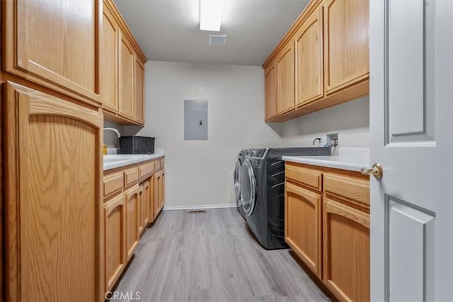laundry room with cabinet space, electric panel, light wood-type flooring, washer and clothes dryer, and baseboards
