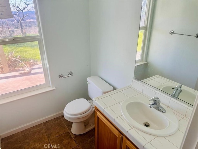 bathroom featuring toilet, baseboards, and vanity
