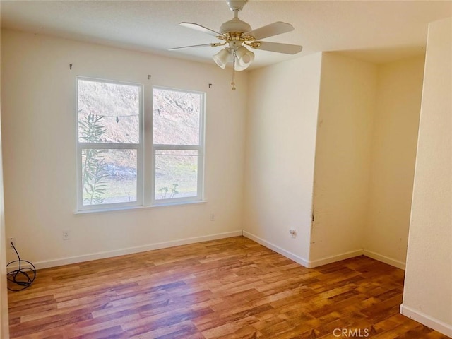 spare room featuring baseboards, a healthy amount of sunlight, ceiling fan, and wood finished floors
