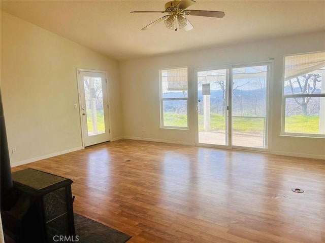 unfurnished living room featuring a wealth of natural light, vaulted ceiling, and wood finished floors