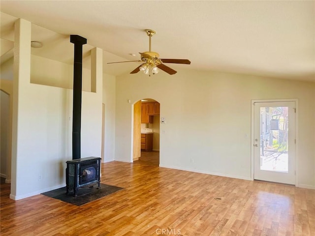 unfurnished living room featuring ceiling fan, light wood-type flooring, lofted ceiling, and arched walkways