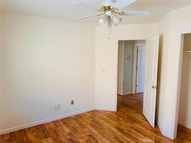empty room with a ceiling fan, baseboards, and wood finished floors
