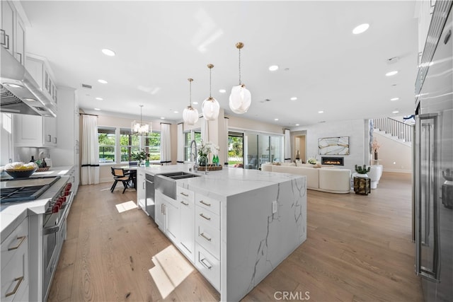 100 Bellatrix, Irvine, CA 92618 - kitchen with a sink, a large island with sink, light wood-type flooring, range hood, and double oven range