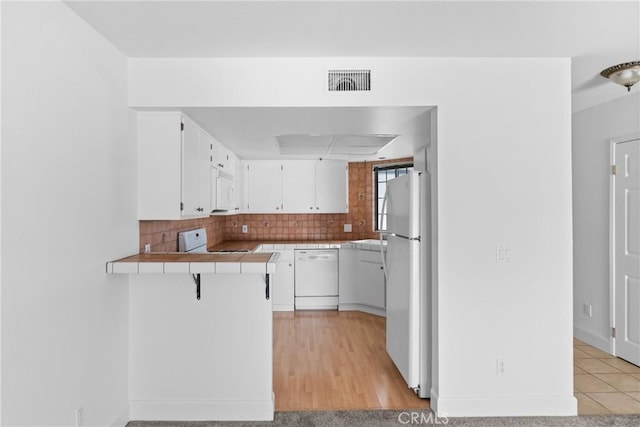 2220 Exposition Dr Unit 64, San Luis Obispo, CA 93401 - kitchen featuring white appliances, a peninsula, white cabinetry, decorative backsplash, and tile counters