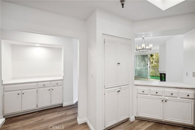 1450 Brett Pl Unit 205, San Pedro, CA 90732 - kitchen with a chandelier, light wood-type flooring, white cabinetry, light countertops, and baseboards