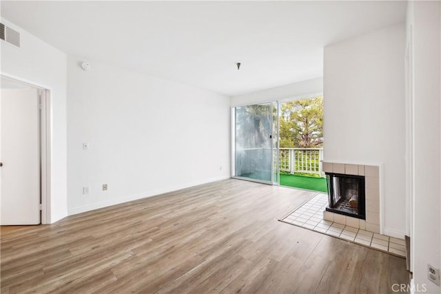 unfurnished living room with baseboards, a fireplace, visible vents, and wood finished floors