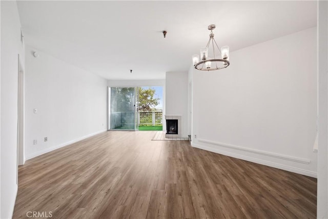 1450 Brett Pl Unit 205, San Pedro, CA 90732 - unfurnished living room featuring wood finished floors, a chandelier, and a fireplace with raised hearth
