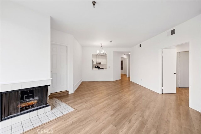 1450 Brett Pl Unit 205, San Pedro, CA 90732 - unfurnished living room with an inviting chandelier, a tile fireplace, visible vents, and light wood-style floors