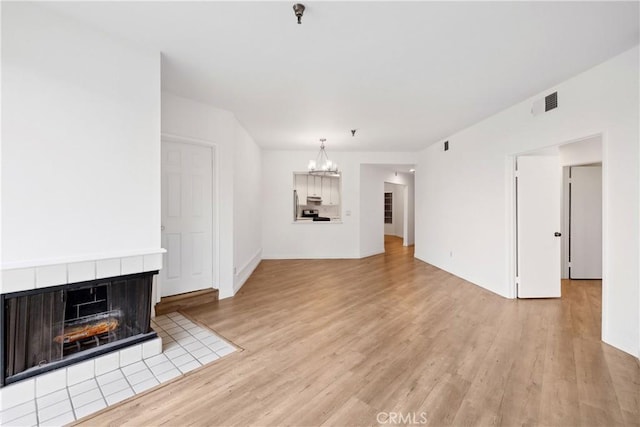 1450 Brett Pl Unit 205, San Pedro, CA 90732 - unfurnished living room with a chandelier, light wood finished floors, and a tile fireplace