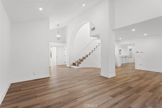 16 Encina, Irvine, CA 92620 - unfurnished living room with light wood finished floors, high vaulted ceiling, baseboards, and stairs