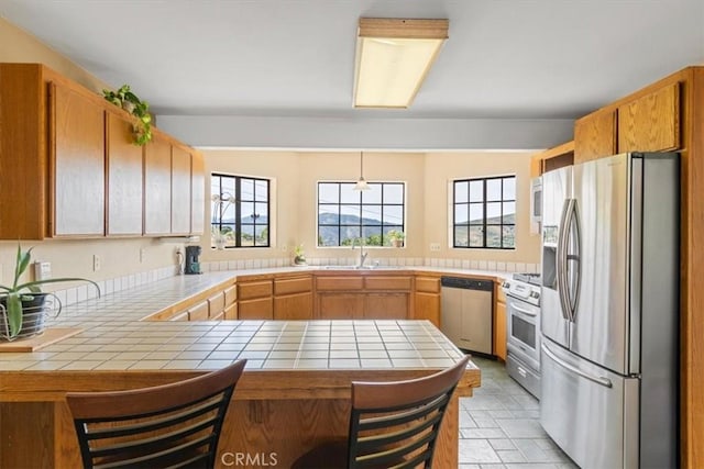 770 Roads End, Lebec, CA 93243 - kitchen with a sink, a peninsula, stainless steel appliances, a breakfast bar, and tile counters