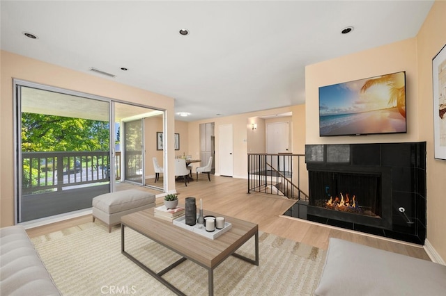 living area with baseboards, a tile fireplace, visible vents, and wood finished floors