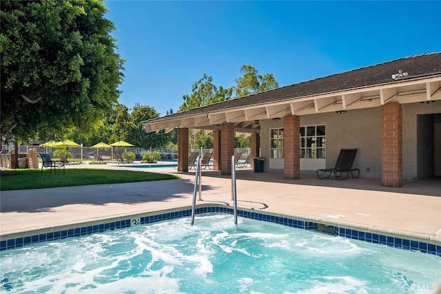 pool with a hot tub, a patio area, and fence