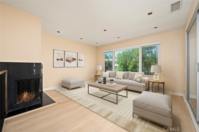 living area featuring wood finished floors, visible vents, recessed lighting, baseboards, and a multi sided fireplace
