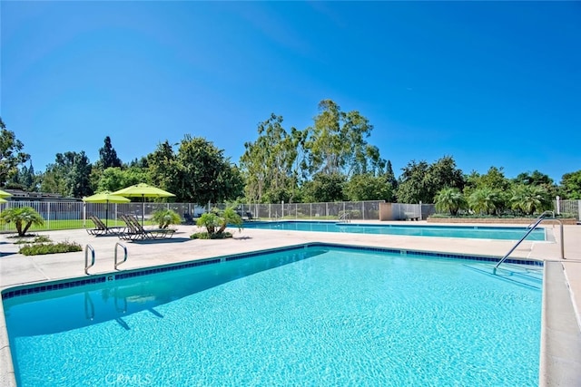 community pool with a patio area and fence