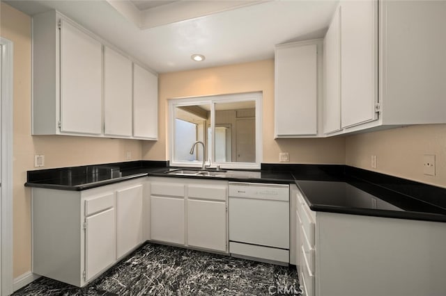 kitchen with dark countertops, dishwasher, white cabinetry, and a sink