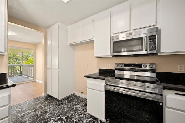 kitchen with white cabinetry, dark countertops, appliances with stainless steel finishes, and baseboards