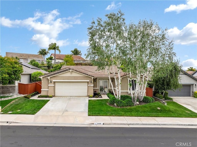 mediterranean / spanish-style home featuring a garage, stucco siding, fence, a front lawn, and concrete driveway