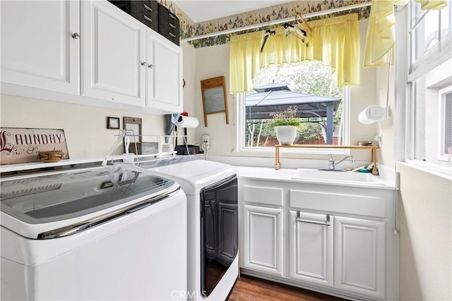 laundry area with washing machine and clothes dryer, light wood finished floors, cabinet space, and a sink