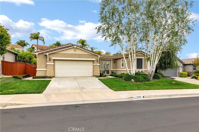 view of front facade with fence, a garage, stucco siding, and a front yard