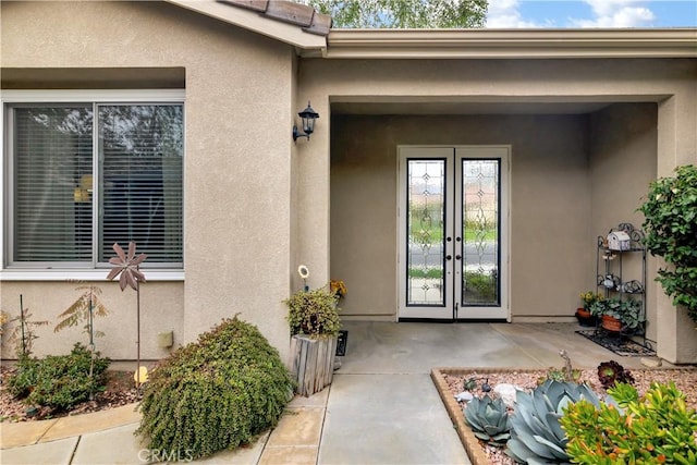 view of exterior entry with a patio, stucco siding, and french doors