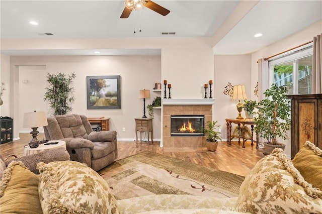 living area with a tile fireplace, wood finished floors, a ceiling fan, baseboards, and recessed lighting