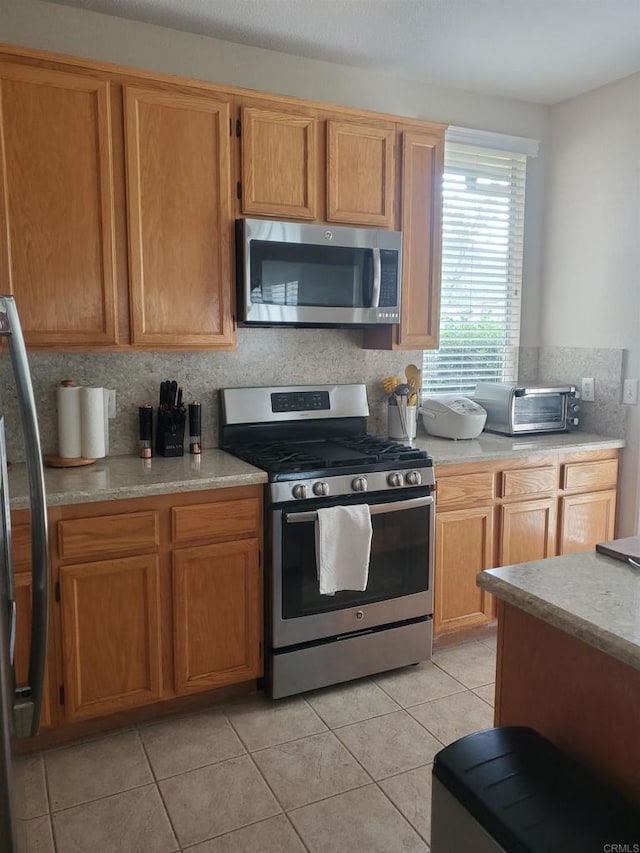 3259 Dehesa Rd Unit 57, El Cajon, CA 92019 - kitchen featuring stainless steel appliances, light countertops, light tile patterned flooring, and backsplash