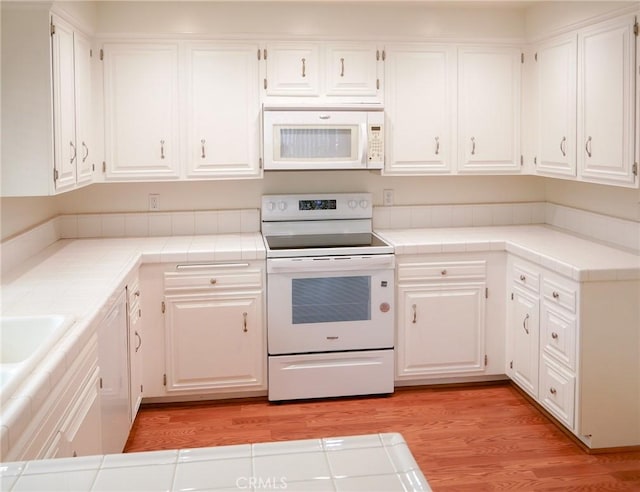 kitchen featuring white cabinetry, white appliances, and tile counters