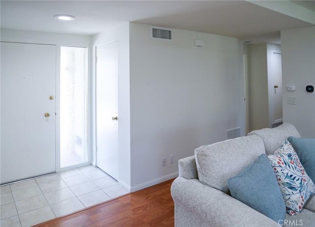 living room featuring baseboards, light wood-style flooring, and visible vents