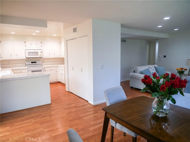 interior space with white cabinetry, white appliances, tile countertops, and recessed lighting