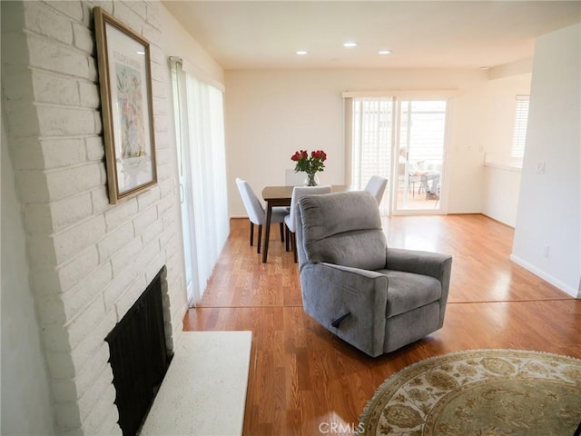 dining area featuring a fireplace, light wood-style flooring, baseboards, and recessed lighting