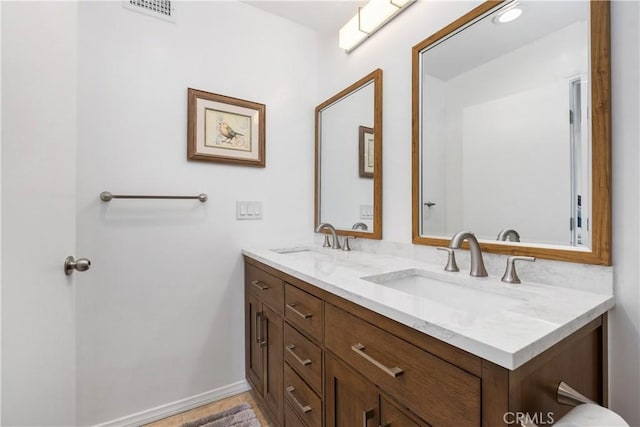 bathroom featuring double vanity, visible vents, baseboards, and a sink